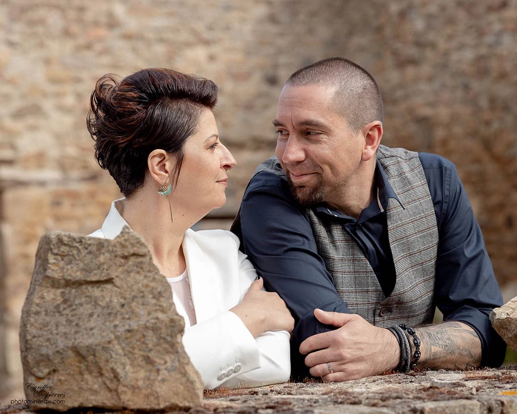 Couple assis devant un mur de pierre
