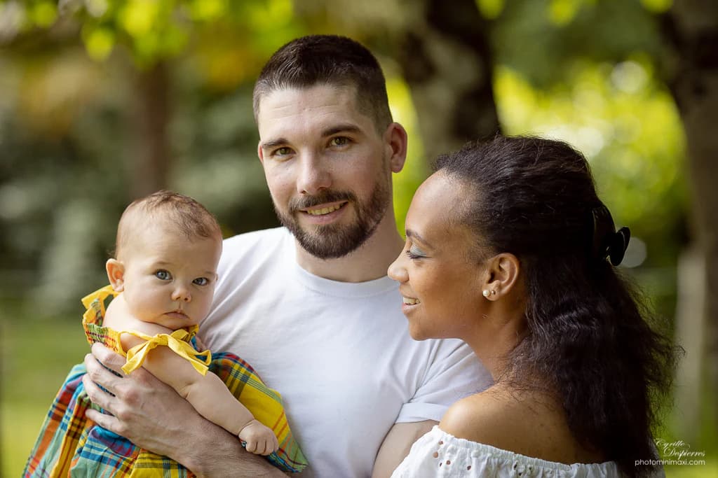Couple souriant tenant un bébé en extérieur